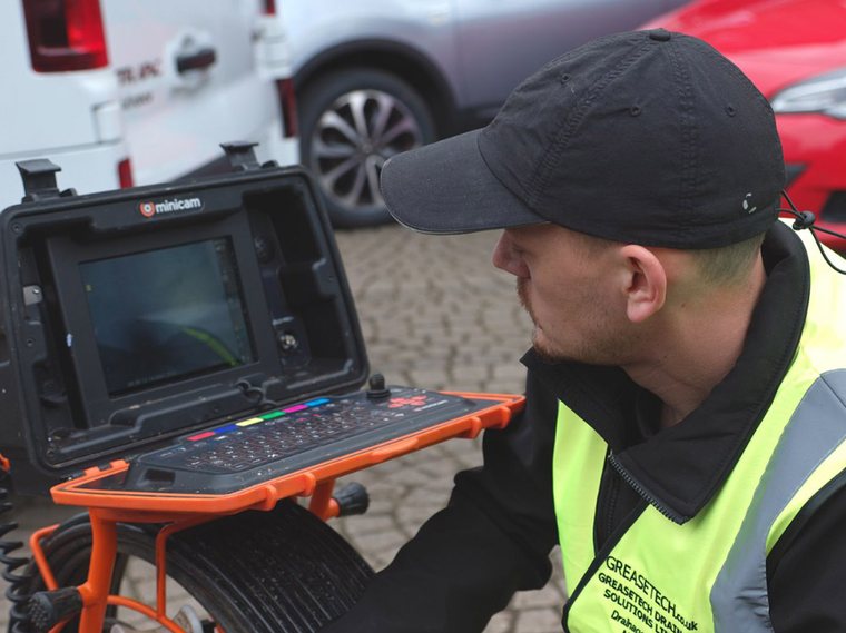 GreaseTech engineer reviewing drain camera footage on a monitor